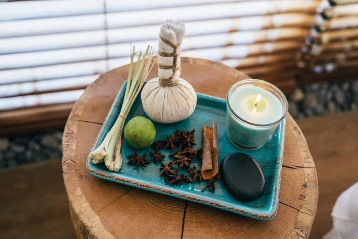 Aromatherapy oils, a lit candle and folded linen arranged on a wooden table