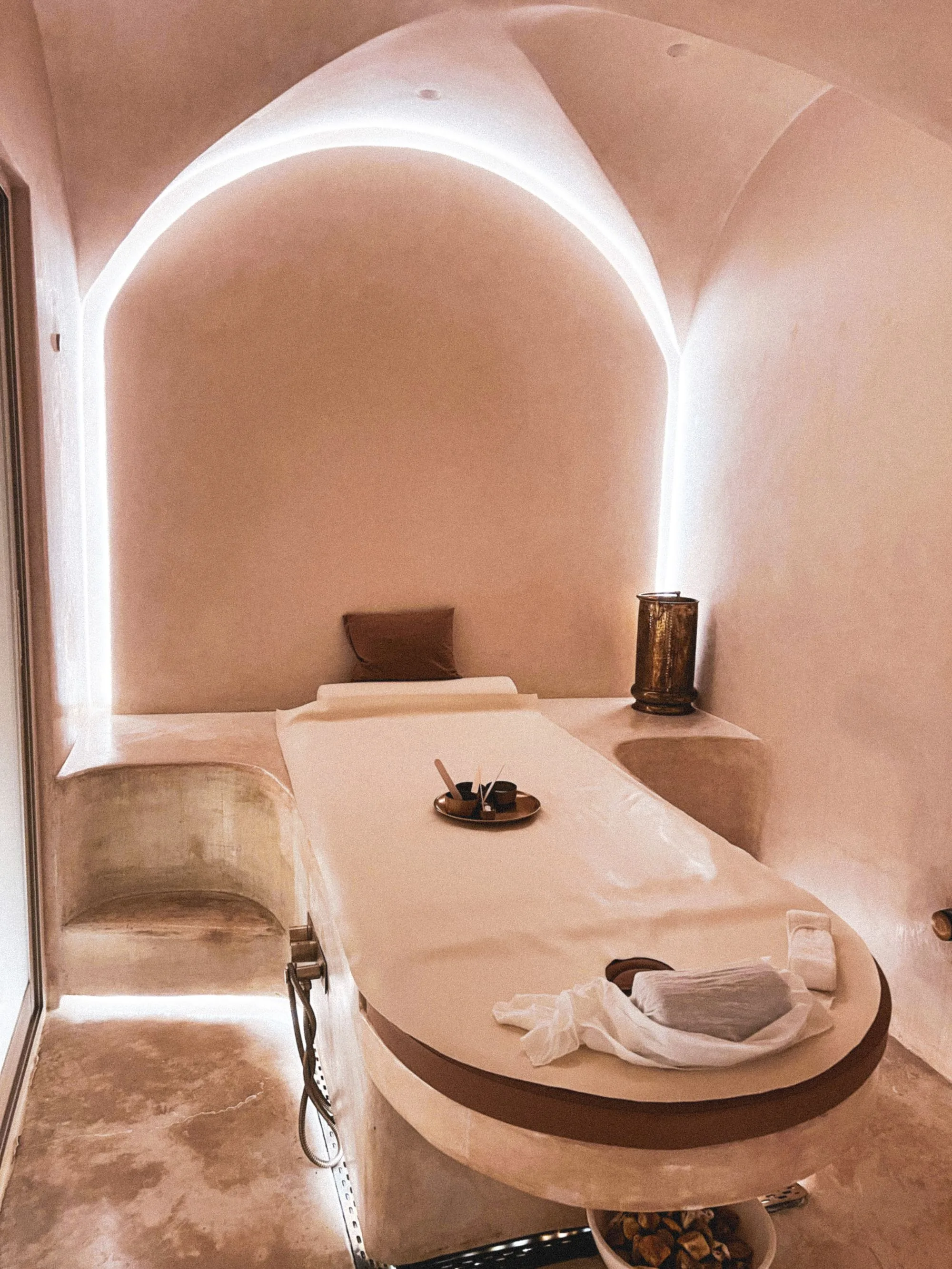 A dimly lit spa suite with candles, warm wood and soft linen